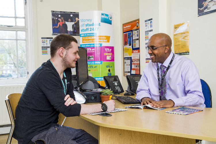 Two people talking at a desk