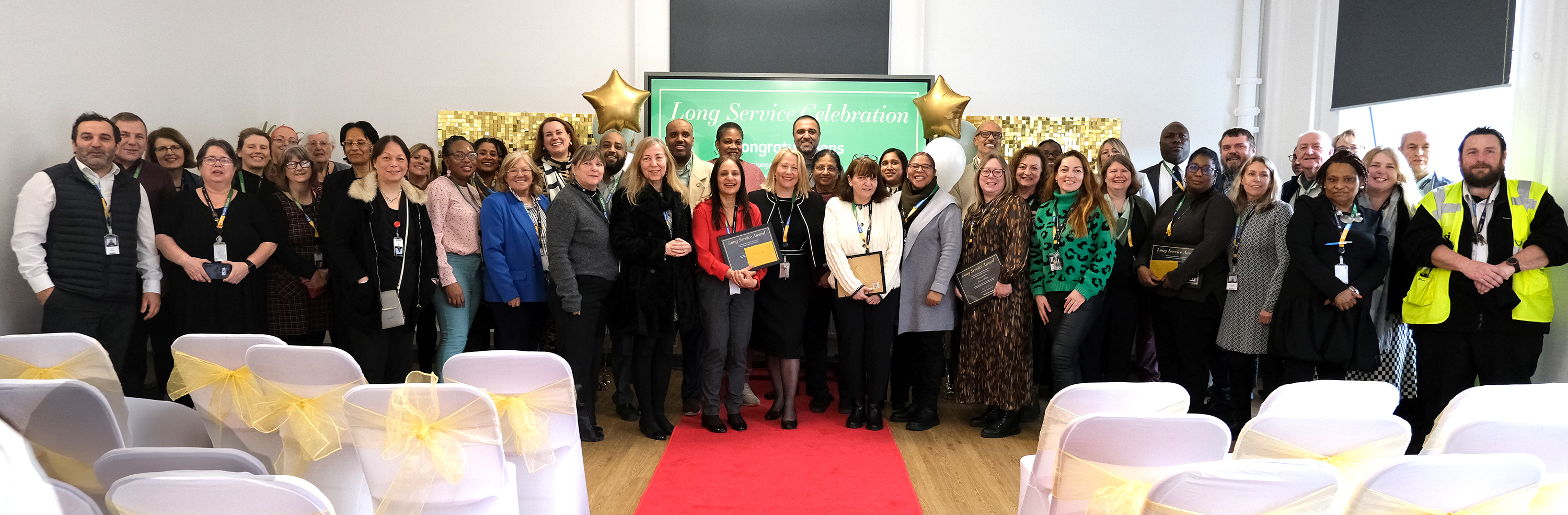All staff who attended the event stand in a long line in front of red carpet for photograph