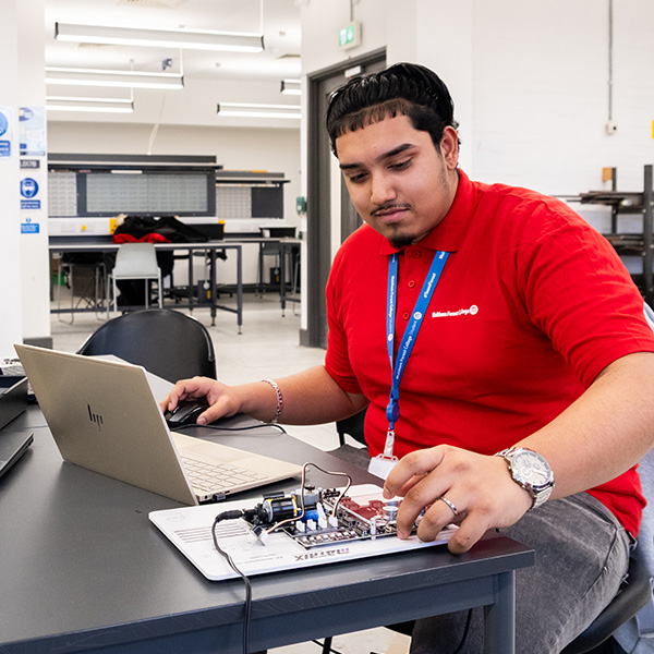 Engineering student with an electronics board and a laptop